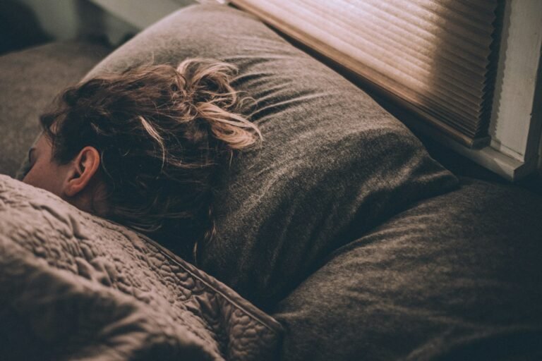Mulher deitada na cama no escuro, sem conseguir dormir