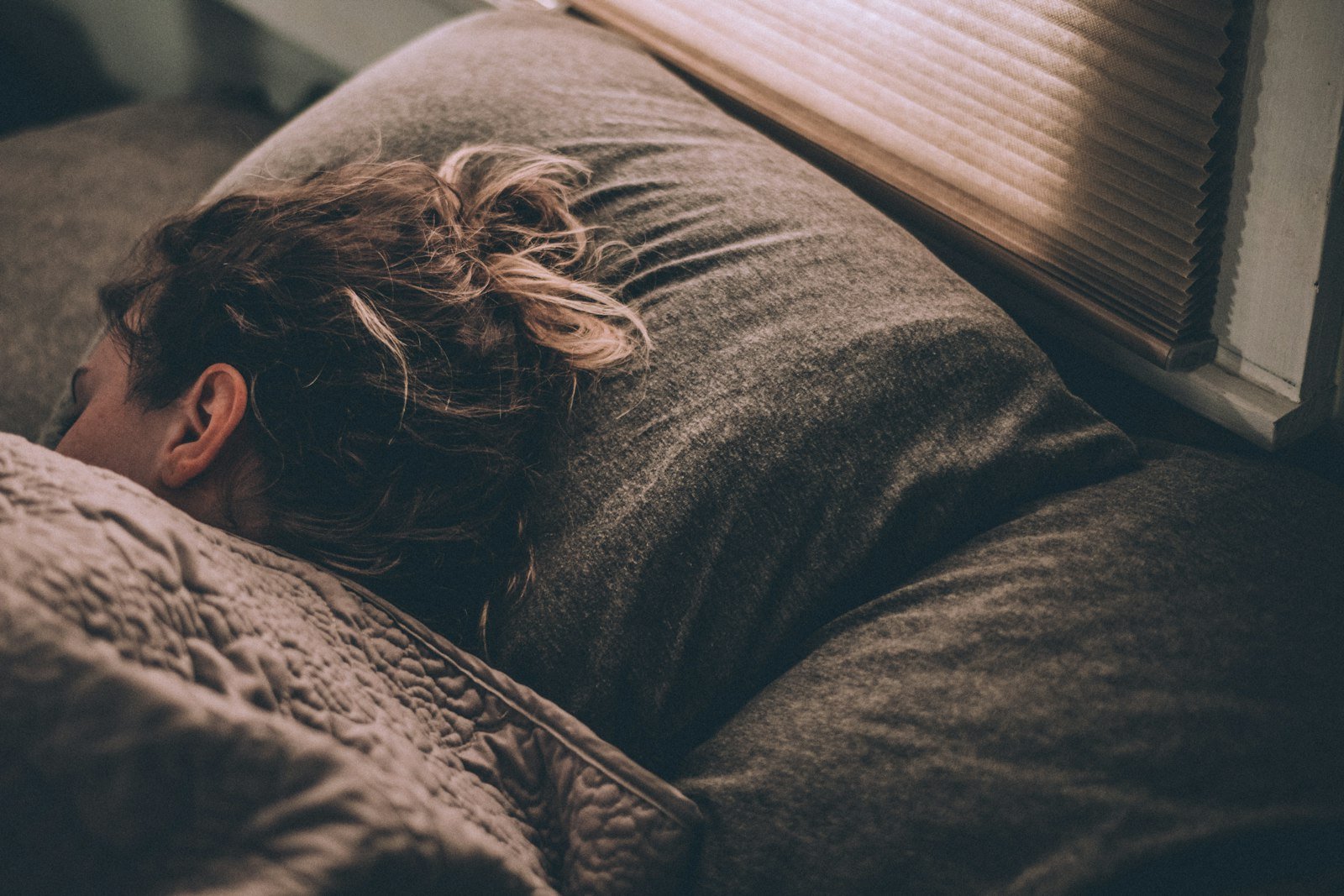 Mulher deitada na cama no escuro, sem conseguir dormir