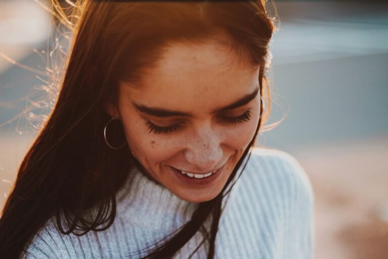 Mulher sorrindo emocionada, olhando para baixo