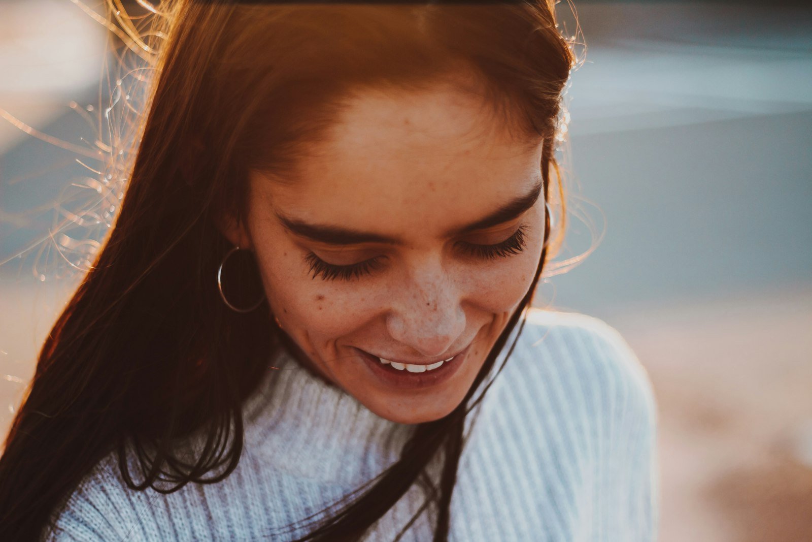 Mulher sorrindo emocionada, olhando para baixo