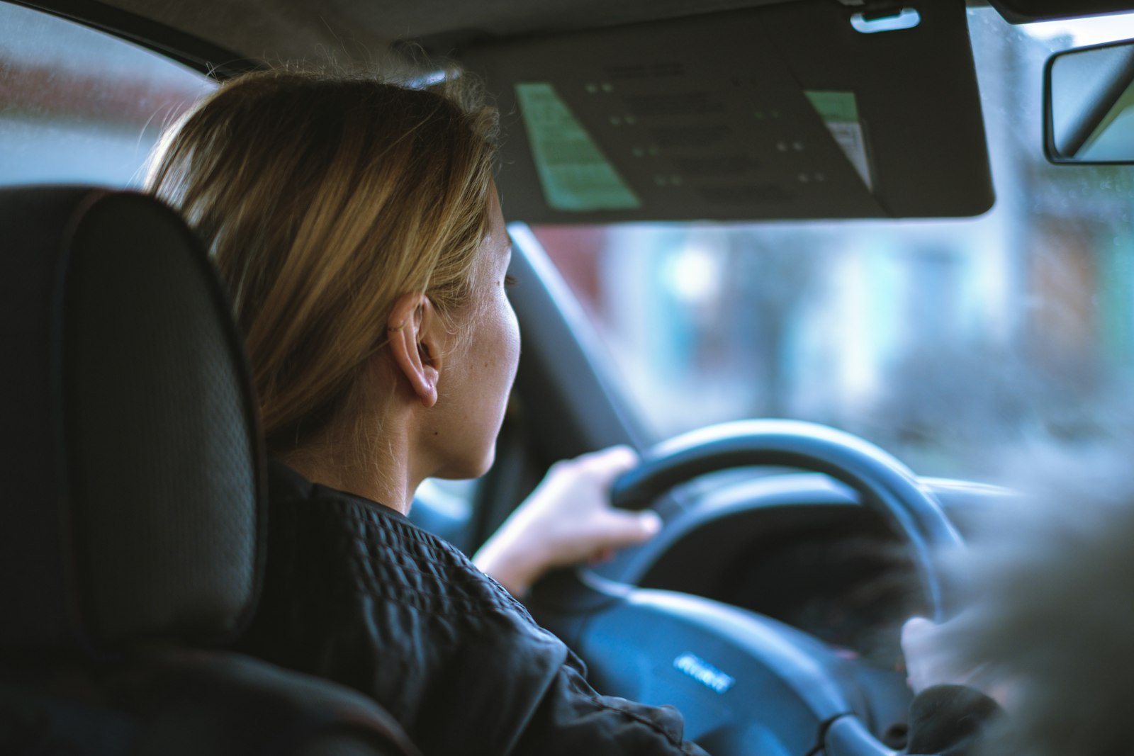 Mulher sentada sozinha ao volante do carro, pensativa